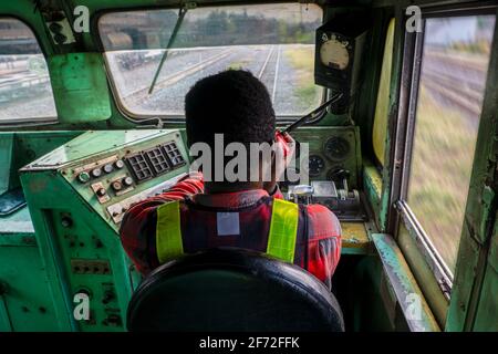Afrikanischer Mann Zugfahrer sitzt innen zu Kontrollplatz von Trainieren Sie mit Sprechfunk Stockfoto