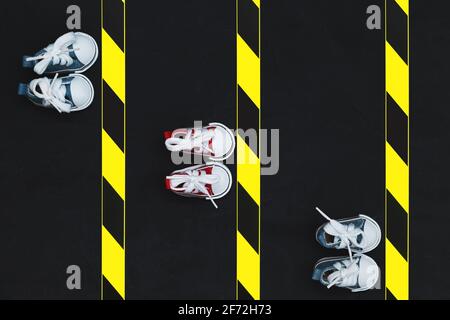 Konzept der sozialen Distanzierung. Turnschuhe und Warnband auf dem Asphalt-Hintergrund. Speicherplatz kopieren. Halten Sie Abstand, um die Ausbreitung des Virus zu verhindern. Neu Stockfoto