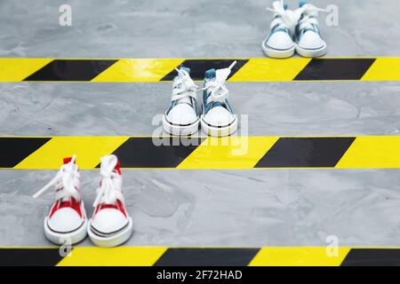 Konzept der sozialen Distanzierung. Turnschuhe und Warnband auf dem Asphalt-Hintergrund. Speicherplatz kopieren. Halten Sie Abstand, um die Ausbreitung des Virus zu verhindern. Neu Stockfoto