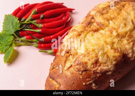 Rutsche von roten Chilischoten mit grünen Blättern und einem Laib Brot. Blick von oben. Stockfoto