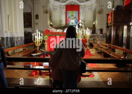 Gläubige im Gebet vor den Statuen des toten Christus und der schmerzhaften Jungfrau am Karfreitagabend, in der Kirche des Leibes Christi. Stockfoto