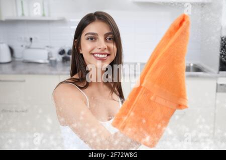 Nahaufnahme von lächelnden jungen Brünette Waschen Glas mit Lappen. Konzept des Reinigungsfensters. Stockfoto