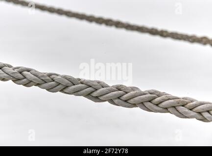 Zwei Segel-Seile, die vom Fischerboot oder von der Yacht hängen, aus der Nähe. Detailliertes Fragment des Seils. Stockfoto