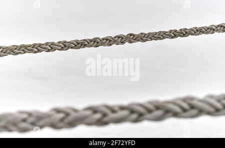 Zwei Segel-Seile, die vom Fischerboot oder von der Yacht hängen, aus der Nähe. Detailliertes Fragment des Seils. Stockfoto