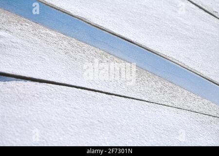 Rissene Eis des gefrorenen Flusses mit weißem Schnee oben und blauem Wasser unten. Hintergrund mit Eisstruktur, Nahaufnahme. Stockfoto