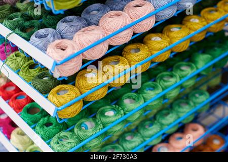 Garne oder Wollkugeln auf Regalen zum Stricken und Nadelarbeiten. Zubehör für Kurzwaren in Stoffregalen. Mehrfarbiger Bildausschnitt, BA Stockfoto