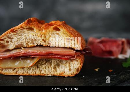 Einfaches Prosciutto Ciabatta-Sandwich in dunkel launischer Umgebung Stockfoto