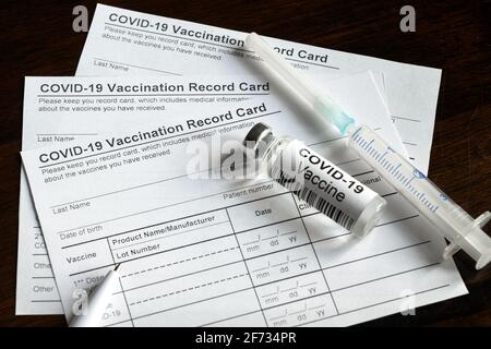 COVID-19 Impfpass auf dem Schreibtisch, Impfpass für Coronavirus und Impfstoffinjektion. Spritze und Impfstoffflasche für Corona-Virus sind Stockfoto