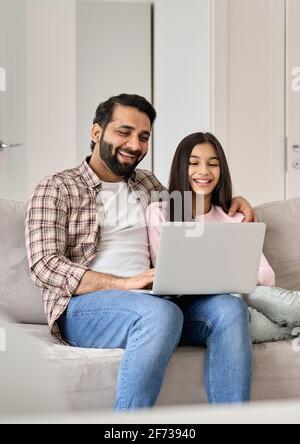 Glücklicher indischer Vater mit Teenager-Tochter, die Spaß mit Laptop zu Hause hat. Stockfoto