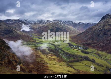 Epische fliegende Drohne Landschaftsbild von Langdale Hechte und Tal Im Winter mit niedrigen Wolken und Nebel wirbeln herum Stockfoto