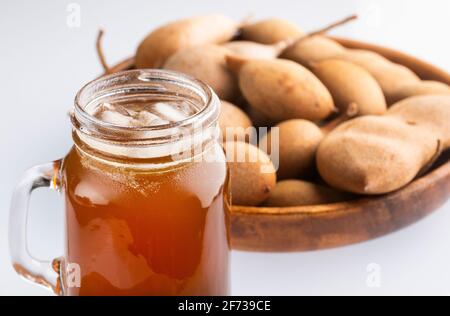 Tamarindus indica - Tamarindensaft in einem Glas, umgeben von Frische reife Tamarinden Stockfoto