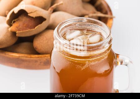 Tamarindensaft in einem Glas, umgeben von frischen reifen Tamarinden - Tamarindus indica Stockfoto