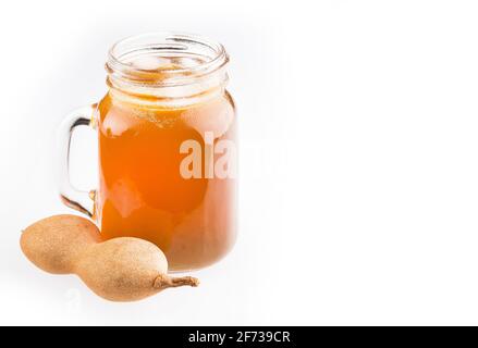 Tamarindensaft in einem Glas, umgeben von frischen reifen Tamarinden - Tamarindus indica Stockfoto