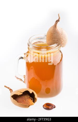 Tamarindensaft in einem Glas, umgeben von frischen reifen Tamarinden - Tamarindus indica Stockfoto