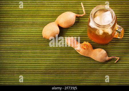 Tamarindensaft in einem Glas, umgeben von frischen reifen Tamarinden Stockfoto