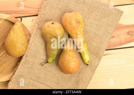 Gruppe von vier reifen Bio süß lecker Konferenz Birnen mit einer Jute Serviette, auf einem natürlichen Holztisch. Stockfoto