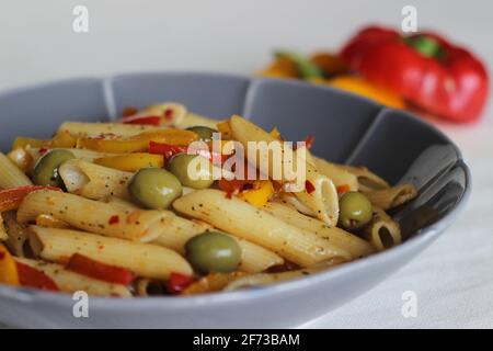 Butter Pasta mit Gemüse. Gekochte Pasta, die in Butter mit Knoblauch und Orangano sautiert und mit Oliven und gebratenem Paprika geschwenkt wird. Auf Weiß geschossen Stockfoto