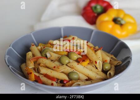 Butter Pasta mit Gemüse. Gekochte Pasta, die in Butter mit Knoblauch und Orangano sautiert und mit Oliven und gebratenem Paprika geschwenkt wird. Auf Weiß geschossen Stockfoto