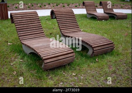 Bank im Park, braune Holzliegen im Erholungsbereich Stockfoto