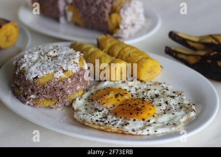 Gedämpfter Hirsemehlkuchen mit einer großzügigen Schicht frischer Kokosnuss dazwischen. Lokal bekannt als Ragi puttu. Serviert mit gedämpftem Kochbananen und Friese Stockfoto