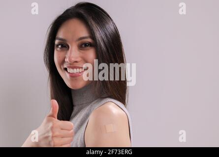 Die junge Frau ist sehr glücklich, gegen sie geimpft worden zu sein Covid-19 Stockfoto