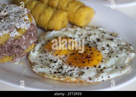 Gedämpfter Hirsemehlkuchen mit einer großzügigen Schicht frischer Kokosnuss dazwischen. Lokal bekannt als Ragi puttu. Serviert mit gedämpftem Kochbananen und Friese Stockfoto