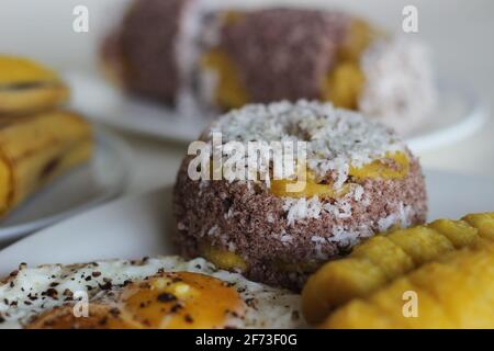 Gedämpfter Hirsemehlkuchen mit einer großzügigen Schicht frischer Kokosnuss dazwischen. Lokal bekannt als Ragi puttu. Serviert mit gedämpftem Kochbananen und Friese Stockfoto