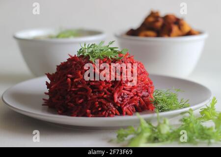 Rote Beete Pulao, ein ein-Topf-Reiszubereitung mit Basmati-Reis, Rote Beete, Zwiebeln und Gewürzen. Serviert mit luftgebratenen Hähnchenbissen und Quark. Auf Weiß geschossen Stockfoto