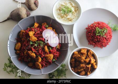 Rote Beete Pulao, ein ein-Topf-Reiszubereitung mit Basmati-Reis, Rote Beete, Zwiebeln und Gewürzen. Serviert mit luftgebratenen Hähnchenbissen und Quark. Auf Weiß geschossen Stockfoto