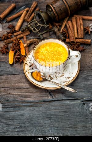 Heißes Kurkuma-Getränk. Goldene Milch mit Gewürzen auf dunklem Holzhintergrund Stockfoto