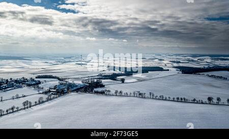 Verschneite Winterlandschaft Mit Abgelegener Siedlungen Und Windenergieanlagen In Österreich Stockfoto