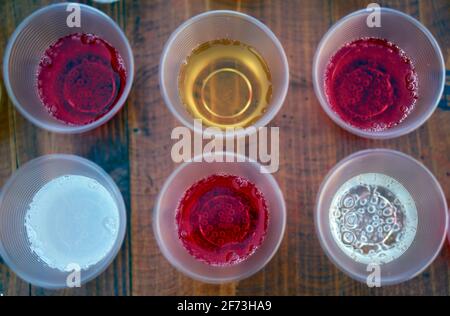 Sommerliches Erfrischungskonzept. Bunte kalte Softdrinks in Plastikgläsern auf Holztisch. Hochwertige Fotos Stockfoto