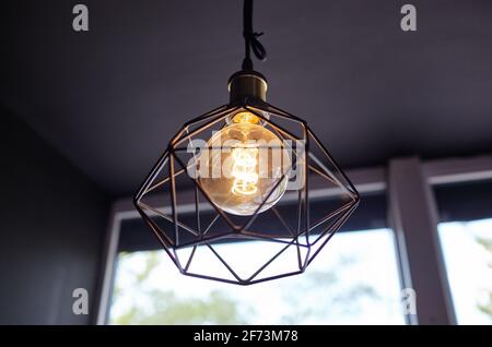 Glühbirne im Loft-Stil, die neben dem Fenster leuchtet. Warmes Licht. Café-Einrichtung Stockfoto