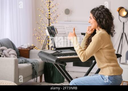 Junge Frau gibt Musikunterricht online zu Hause Stockfoto