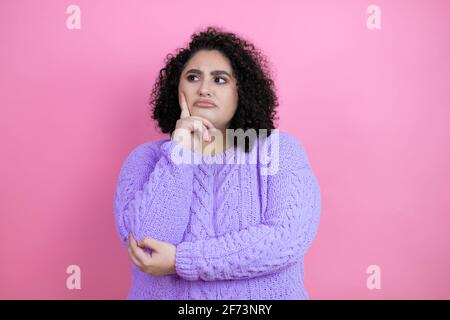 Junge schöne Frau trägt lässigen Pullover über isoliert rosa Hintergrund ernstes Gesicht denken über Frage mit der Hand auf dem Kinn, nachdenklich über Co Stockfoto