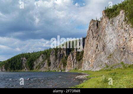 Das Ufer des nördlichen Flusses mit steilen hohen felsigen Ufern, mit Wald überwuchert.die Landschaft der nördlichen Natur Stockfoto