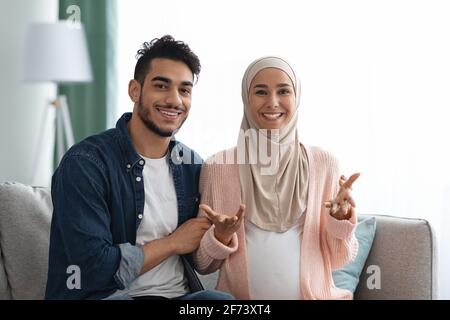 Frohe Nachrichten. Fröhliches, Schwanger-Muslimisches Paar, Das Vor Der Kamera Spricht Und Eine Schwangerschaftsankündigung Macht Stockfoto
