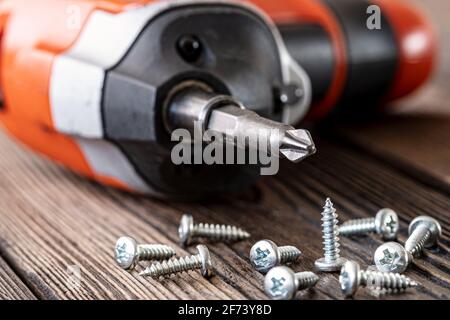 Selbstschneidende Schrauben auf dem Hintergrund eines Schraubendrehers, Befestigungselemente für verschiedene Materialien von Wänden und Oberflächen Stockfoto