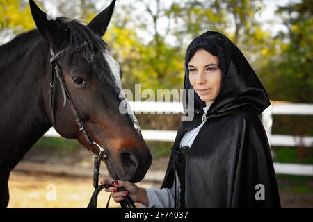 Porträt eines schönen Mädchen im mittelalterlichen Stil gekleidet, hält das Mädchen ein Pferd am Zaumzeug Stockfoto