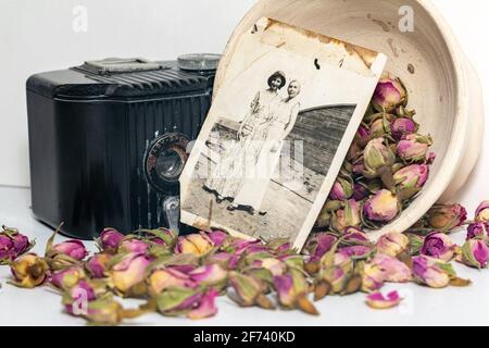 Alte Erinnerungen; Omas alte Baby-Brownie-Kamera, alte Fotos und getrocknete Rosen. Stockfoto