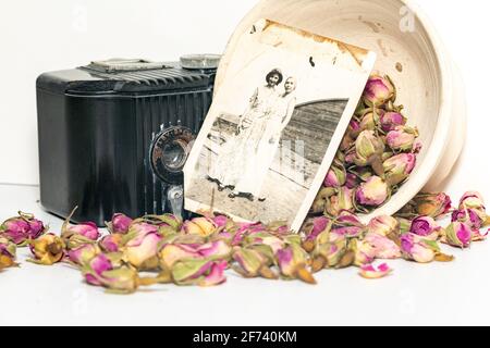 Alte Erinnerungen; Omas alte Baby-Brownie-Kamera, alte Fotos und getrocknete Rosen. Stockfoto