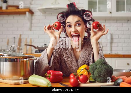 Glückliche junge Frau, die Spaß beim Kochen gesunde vegetarische Mahlzeit In der Küche Stockfoto