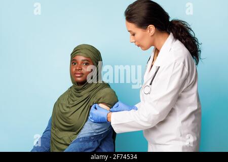 Afrikanische Muslimische Patientin, Die Impfungen Gegen Covid-19 Erhält, Blauer Hintergrund Stockfoto