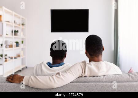 Schwarze Familie beim Fernsehen mit Mockup, auf der Couch sitzend Stockfoto