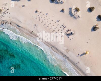 Türkisfarbener Sandstrand mit Menschen, Sonnenliegen und Rettungsschwimmerturm von oben. Entubadera Strand in Corralejo, Fuerteventura Luftbild Stockfoto