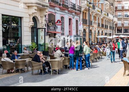 Huelva, Spanien - 1. April 2021: Menschen, die auf der Terrasse eines Cafés und einer Bar auf dem Platz Plaza de las Monjas (Nonnen-Platz) von Huelva sitzen, tragen ein p Stockfoto