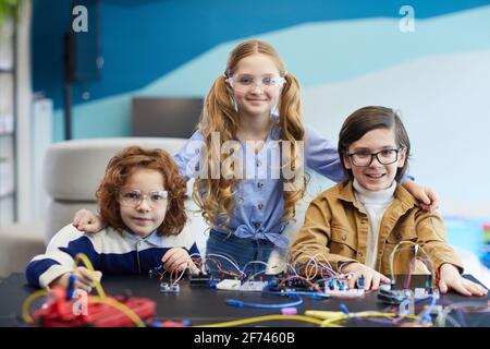 Vorderansicht Porträt von drei Kindern, die Roboter in der Ingenieurskunst bauen Klasse und lächelnd vor der Kamera Stockfoto