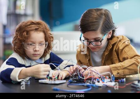 Portrait von zwei Jungen, die Roboter bauen und mit elektrischen experimentieren Schaltungen im Ingenieursunterricht in der Schule Stockfoto