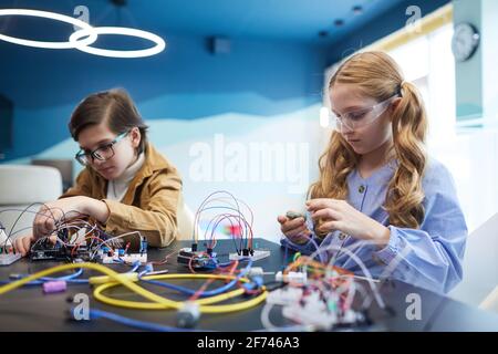 Portrait von zwei Kindern, die Roboter bauen und mit elektrischen experimentieren Schaltungen im Ingenieursunterricht in der Schule Stockfoto