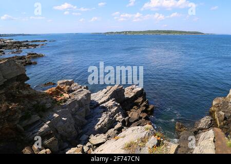 Ocean Bay von oben auf einer Klippe mit Felsvorsprung, blauem Himmel, hellen Wolken und einer Insel am Horizont Stockfoto